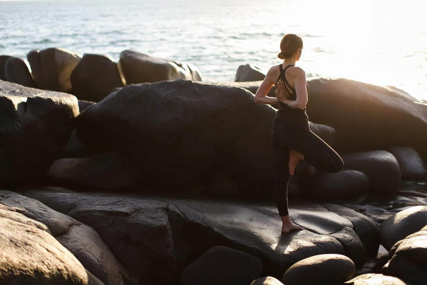 a woman stands on a stone by the sea