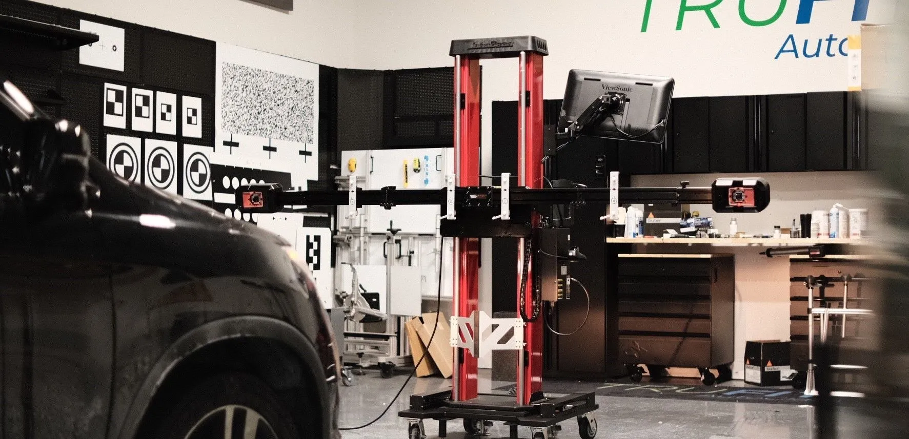 Black car in front of a calibration machine inside an auto glass shop