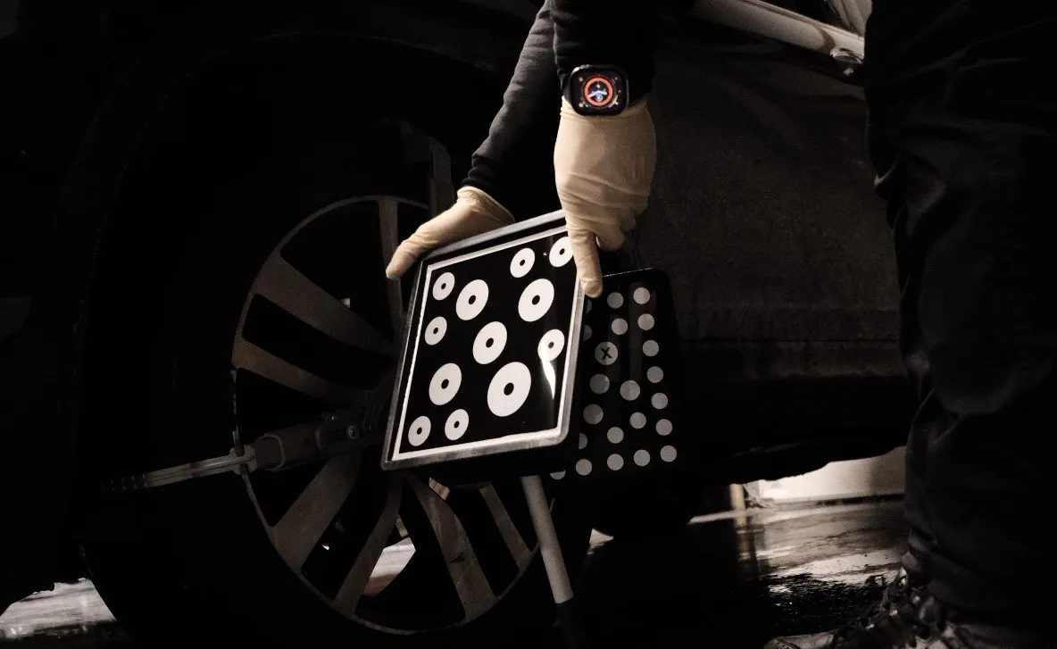Close up of ADAS calibration targets on a car wheel being adjusted by a technician with white gloves on