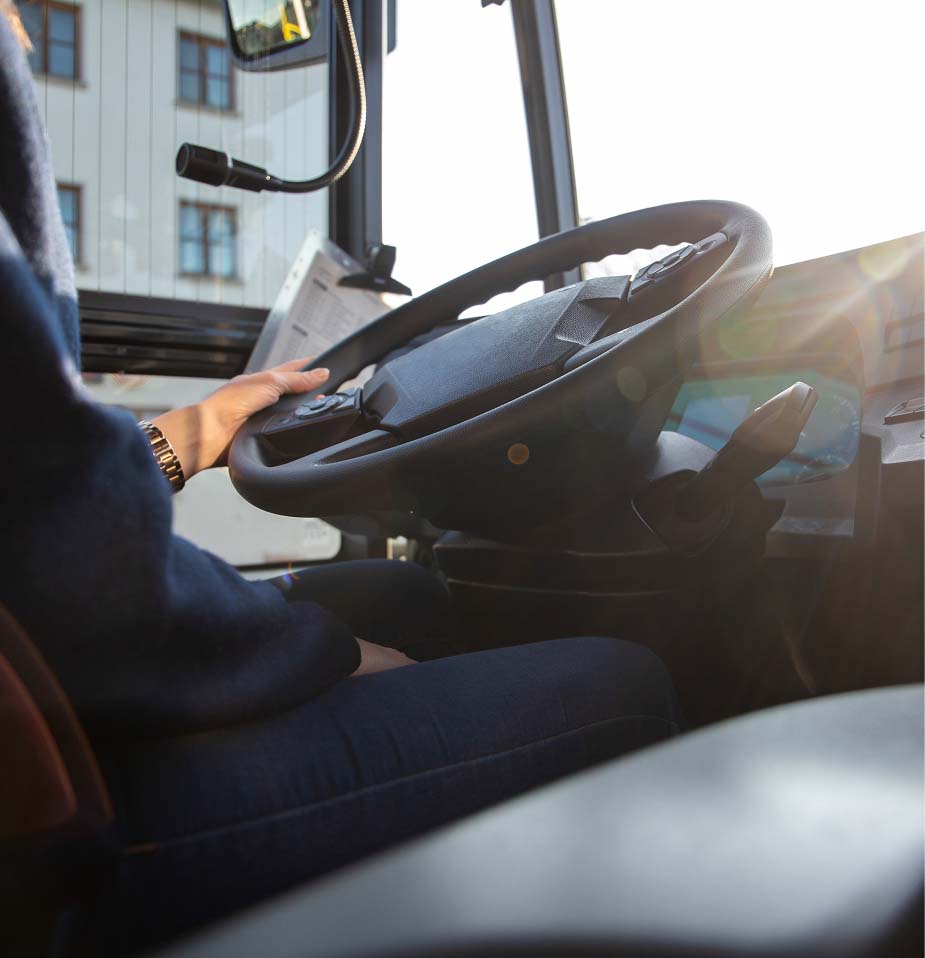 Bus driver seated with hands on the steering wheel
