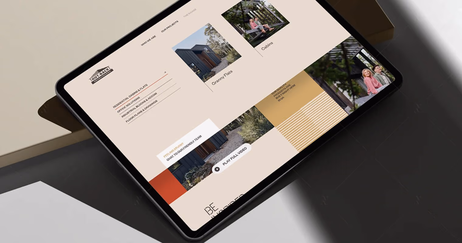 Tablet mockup displaying an Outback Building Group website design with property imagery and a colour palette section, shown at an angle on a dark surface.