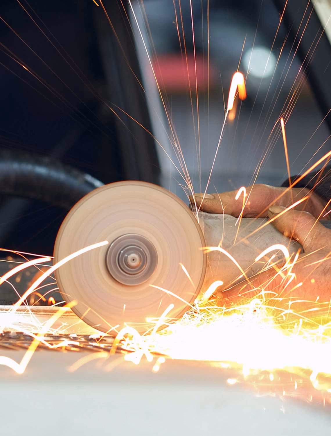 man using grinder in car garage