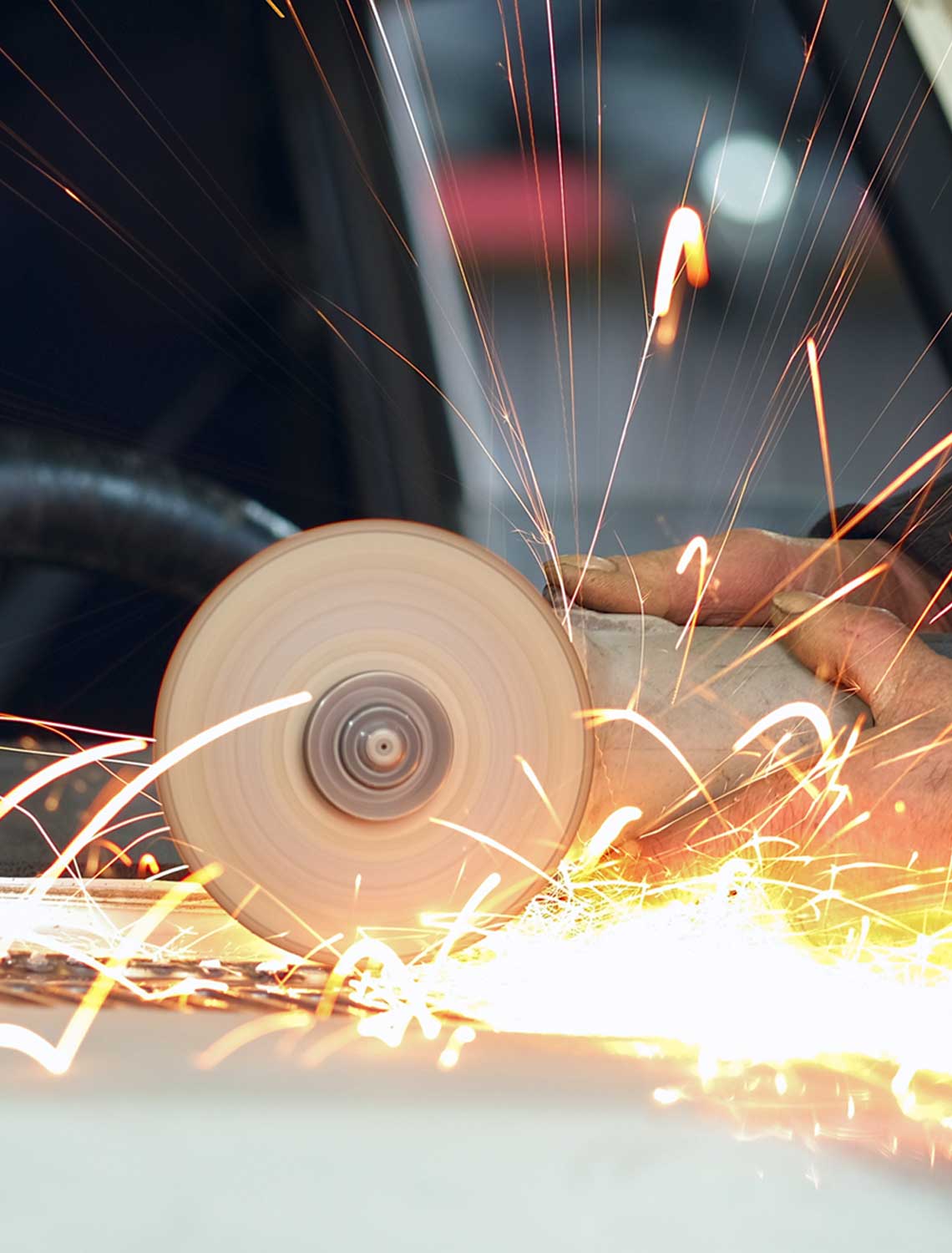 man using grinder in car garage