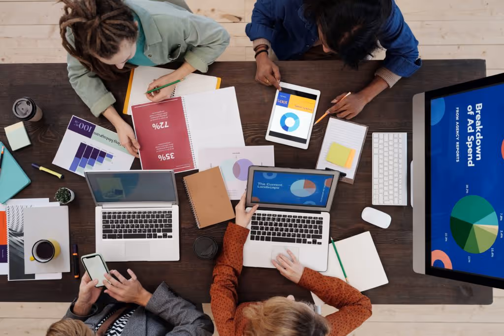 Overhead view of a marketing team working at a cluttered table on their affiliate marketing strategy