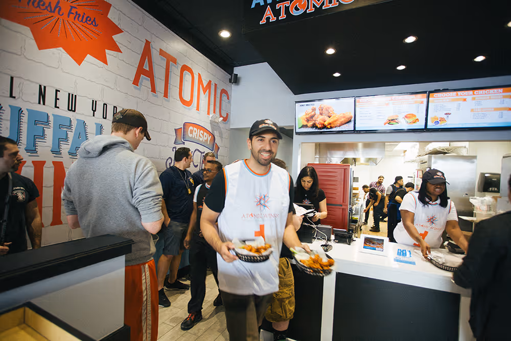 Zak Omar delivering wings to a table at an Atomic Wings