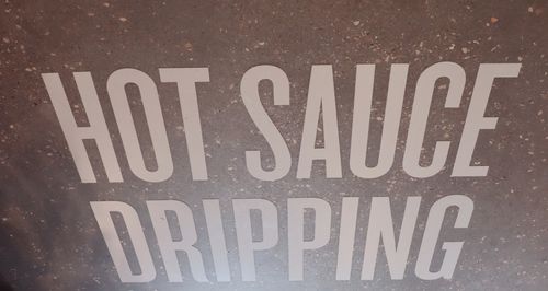 Image of a floor print at an Atomic Wings location with the words "Hot Sauce Dripping"