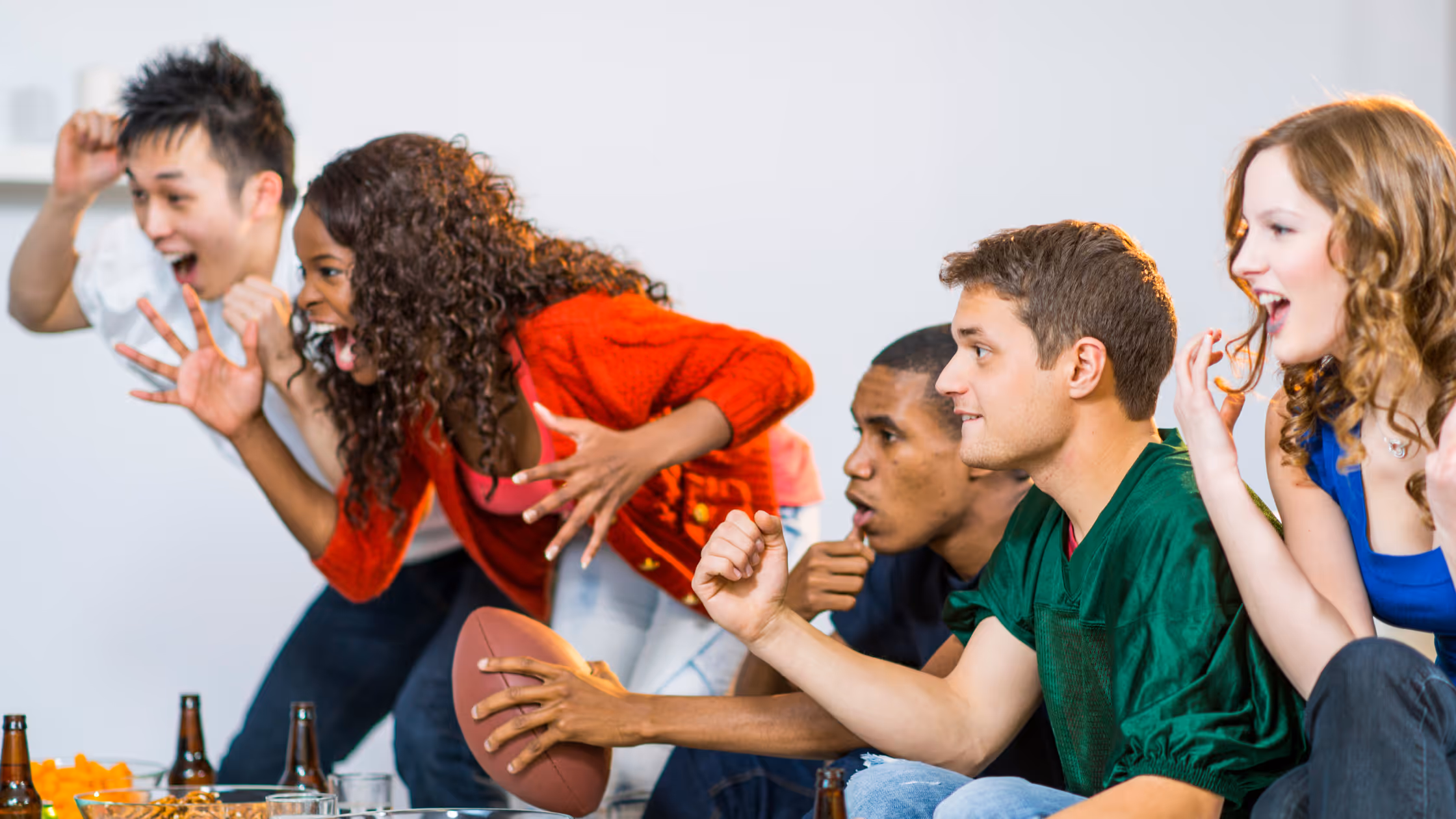 friends at a college football watch party cheering on their team