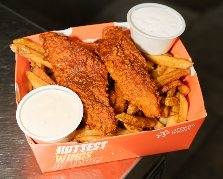 The Atomic Wings $7.99 Slap Box meal featuring two crisp chicken tenders served over fresh-cut fries with two signature sauces