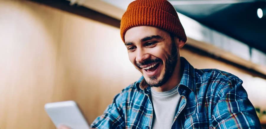 Man smiling while opening a Student Checking account on his phone.