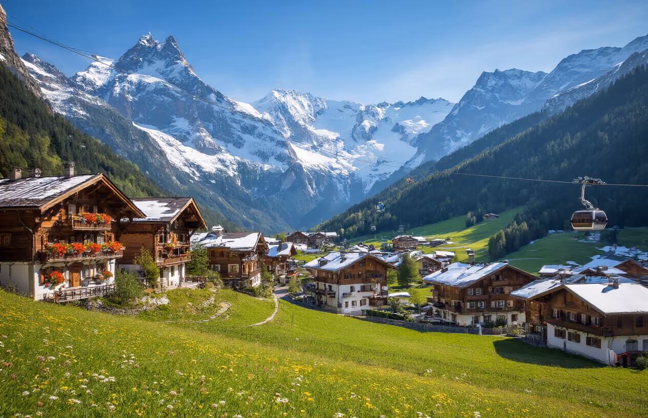 Create a realistic image of a stunning French Alpine mountain village nestled in a snow-capped valley with traditional wooden chalets featuring steep roofs and flower boxes, cable cars or ski lifts visible in the background ascending the mountainside, crystal clear blue skies with dramatic mountain peaks, lush green meadows in the foreground during summer season, and subtle signs of luxury tourism infrastructure like well-maintained hiking trails and mountain lodges, captured during golden hour lighting that highlights the majestic Alpine scenery, absolutely NO text should be in the scene.