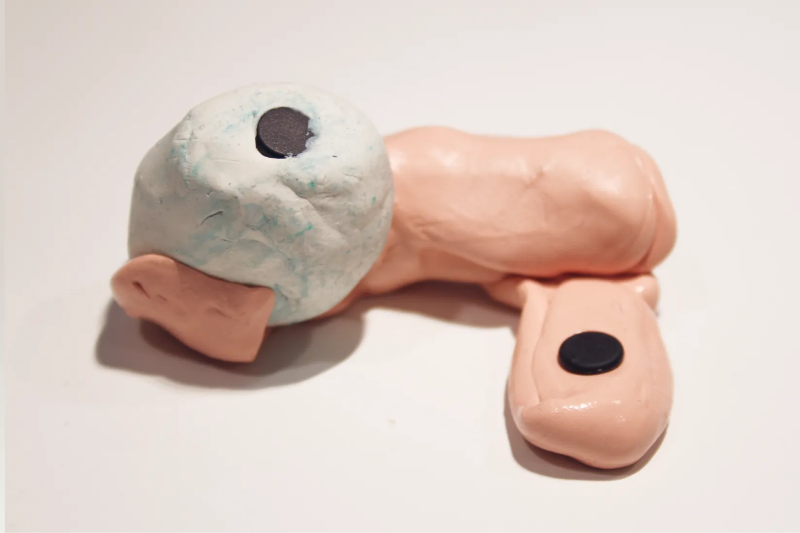 Clay toy prototype shaped like a gun with an RFID stuck into a rounded oversized head/muzzle area and another tag on the trigger/grip area.