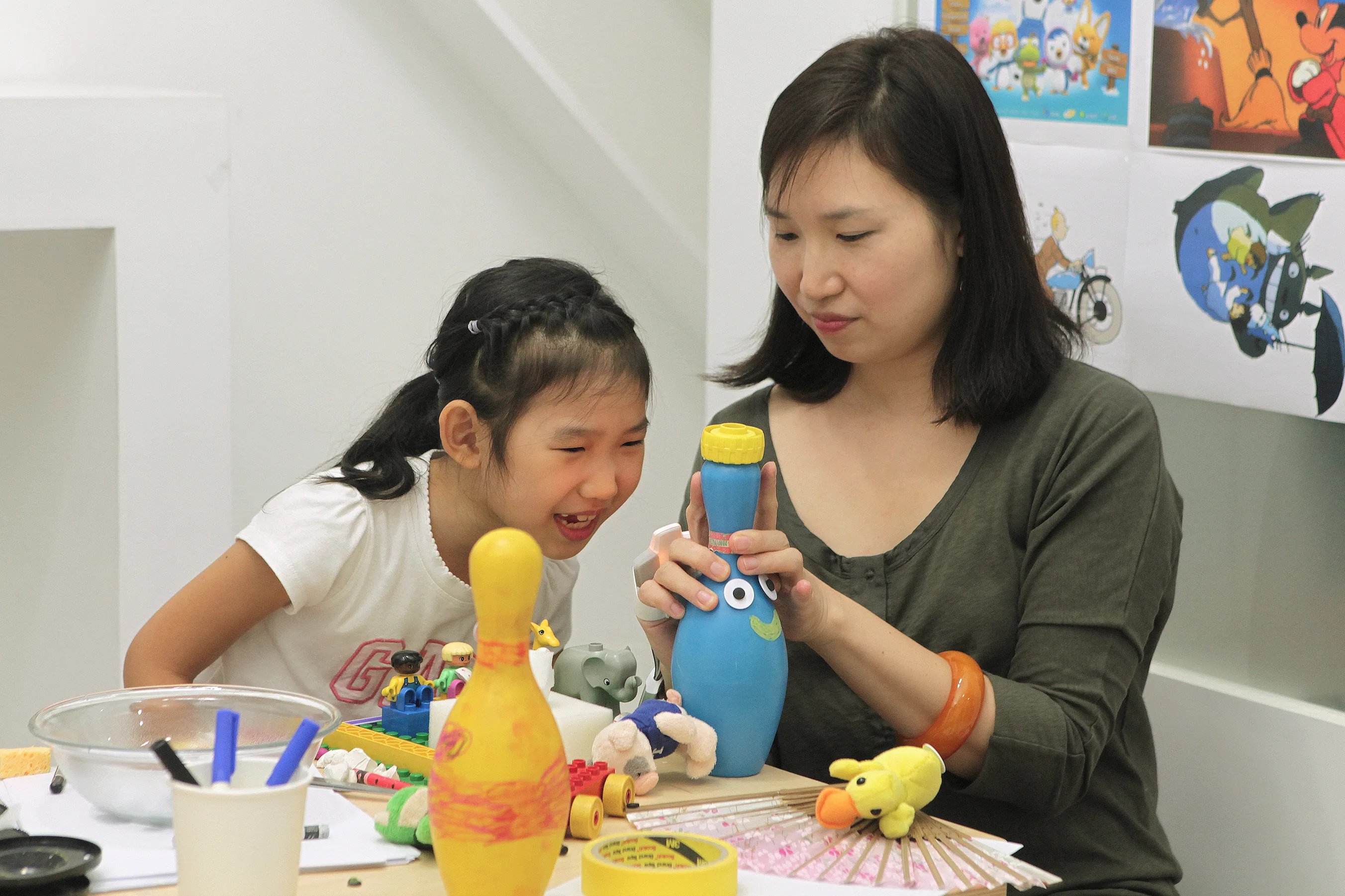 A mother and child explore a playful tangible interaction together at a table; the mother wears an OnObject sensing device on her right hand while guiding the interaction.