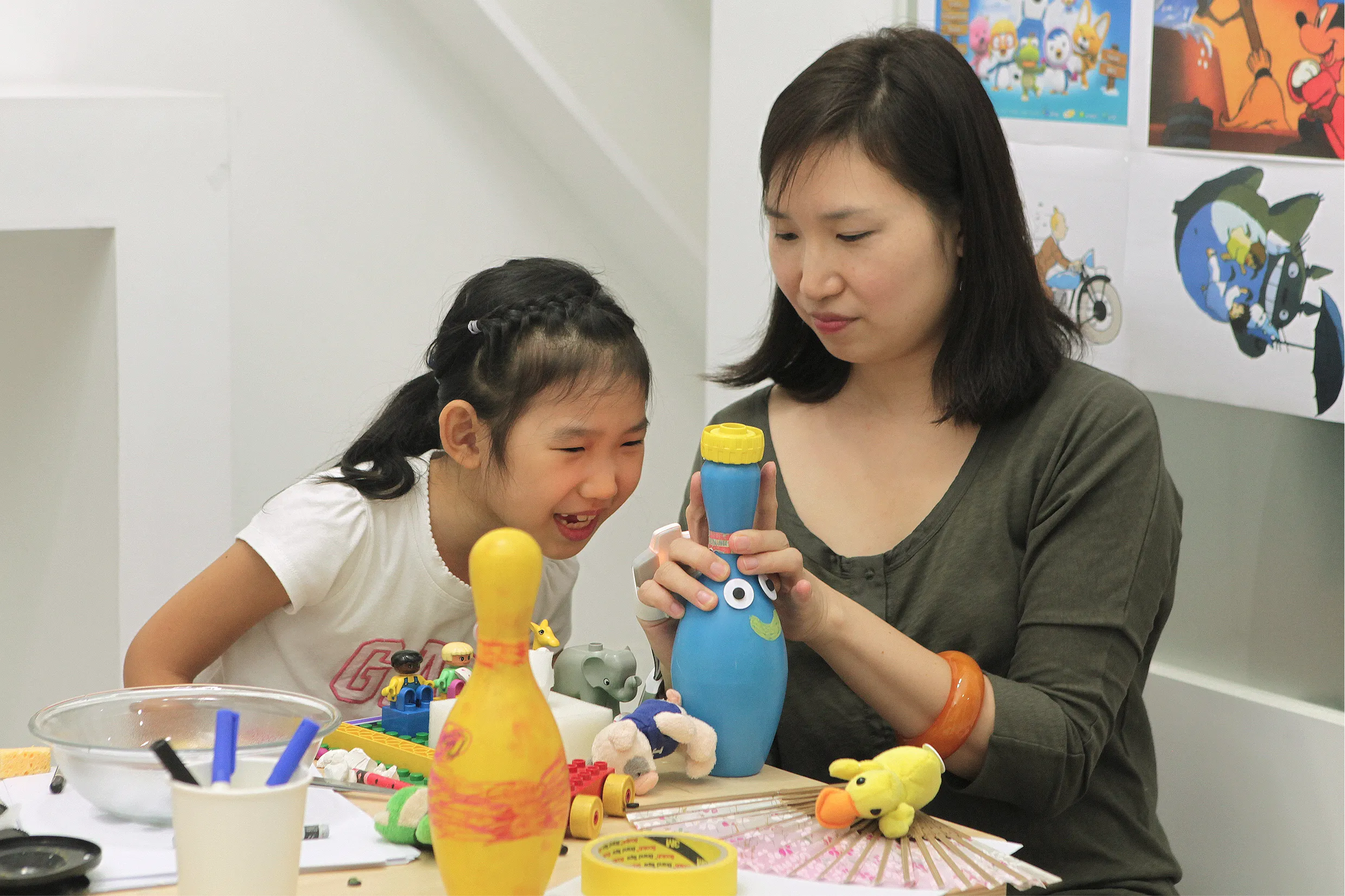 A mother and child explore a playful tangible interaction together at a table; the mother wears an OnObject sensing device on her right hand while guiding the interaction.