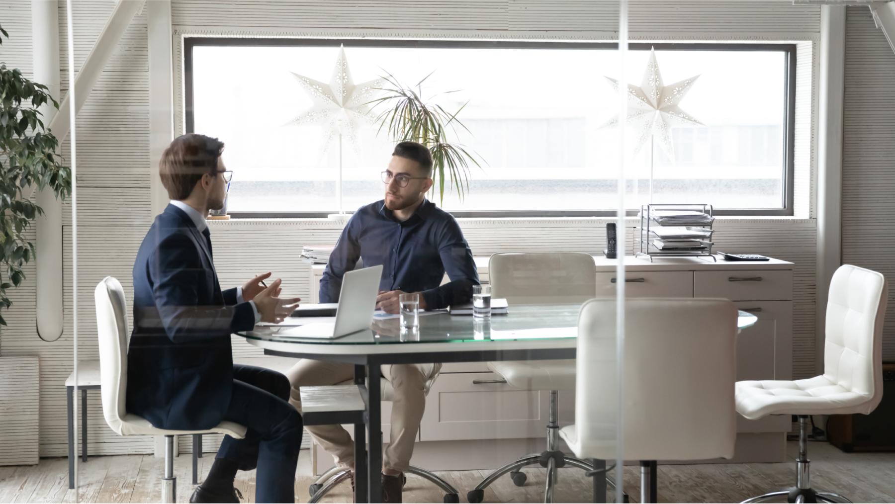 Two young men talking together at a conference table.