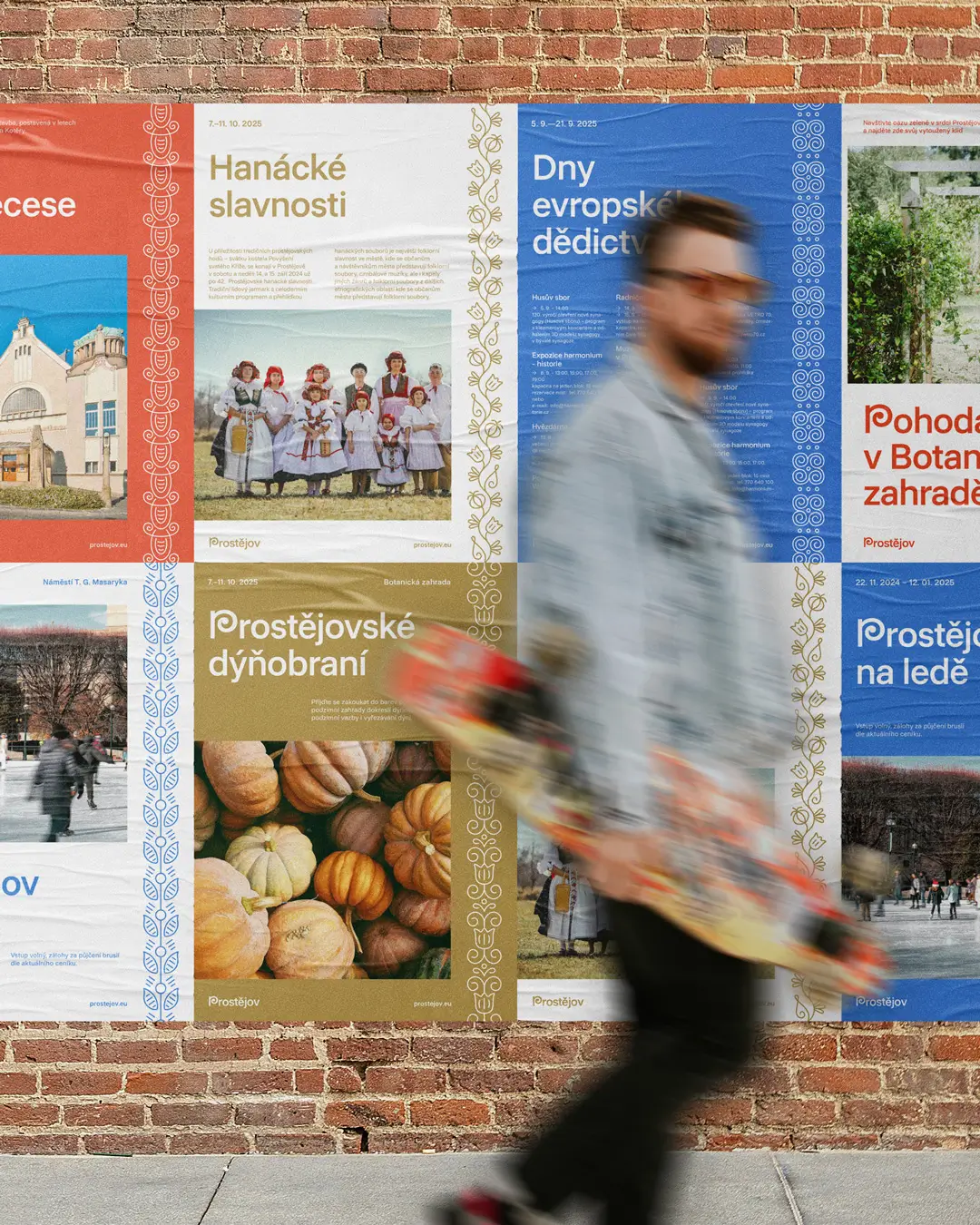 Série plakátů města Prostějov propagujících Hanácké slavnosti, Dny evropského dědictví a Prostějovské dýňobraní, nalepená na cihlové zdi. V popředí prochází mladý muž s longboardem.