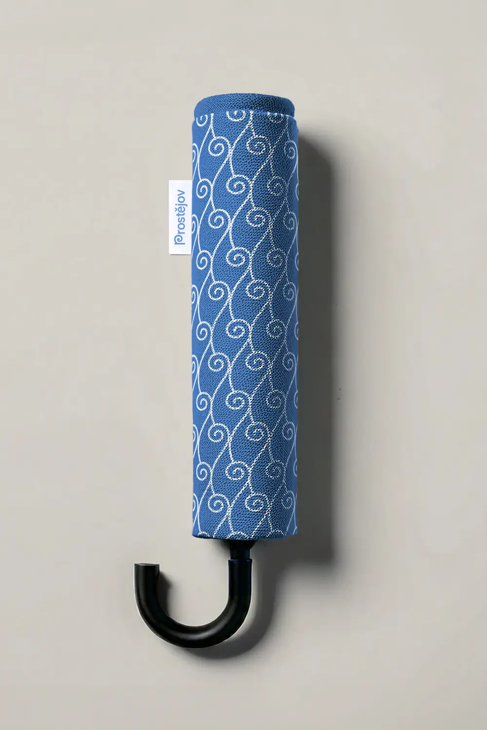 Modrý skládací deštník s bílým ornamentálním vzorem a logem Prostějov na štítku.