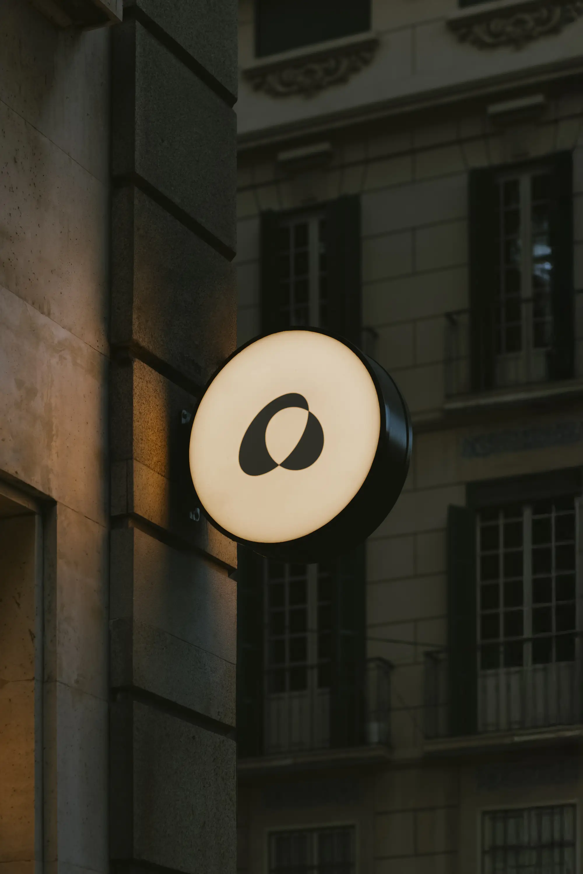 Kruhové světelné znamení s logem Alexa Optika na fasádě historické budovy v Olomouci.