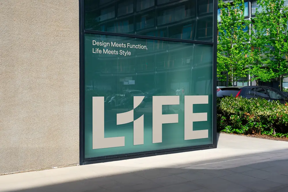 Velkoformátový nápis L1FE na prosklené fasádě moderního bytového domu, součást vizuální identity rezidenčního projektu.