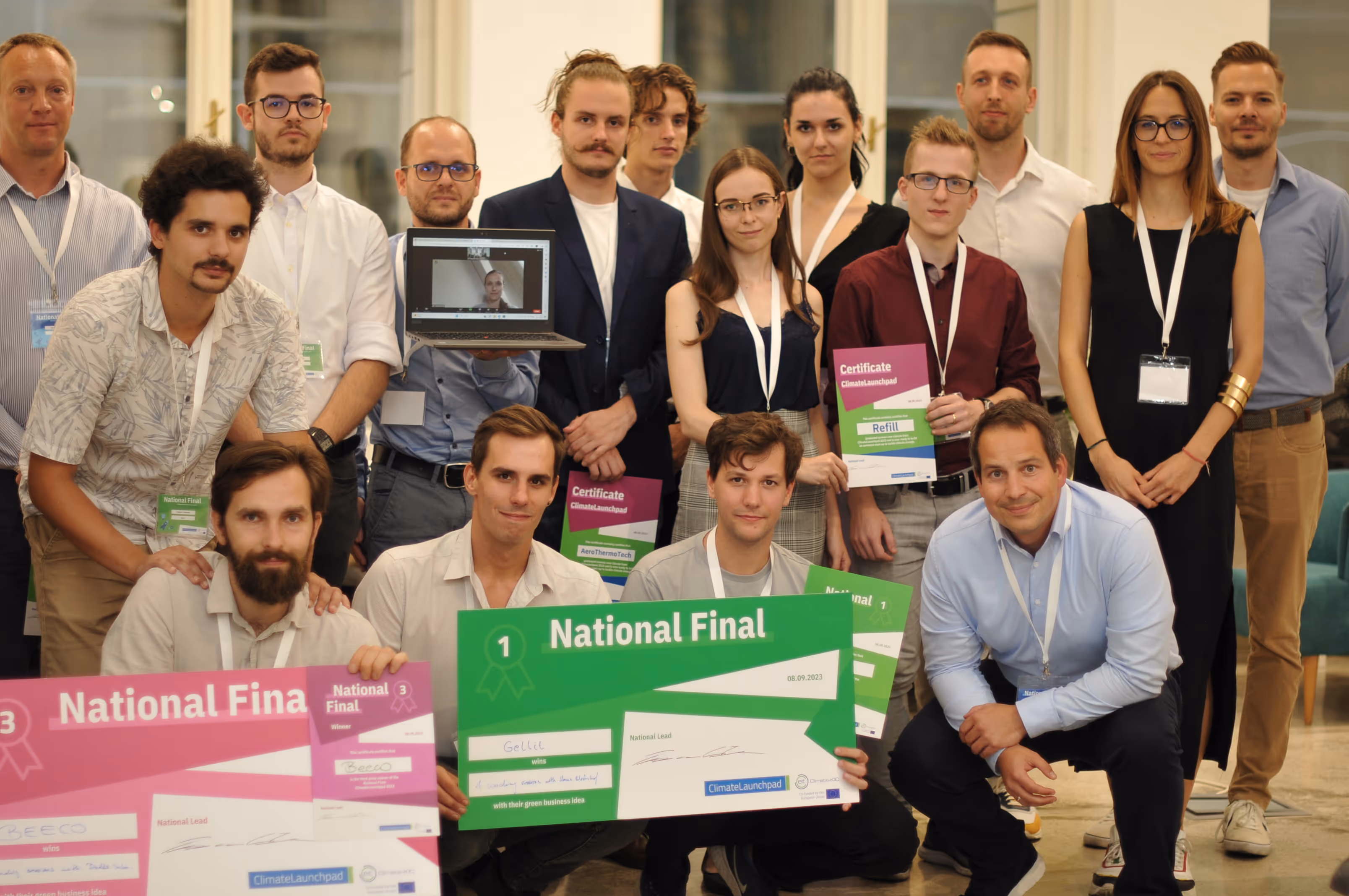 Csoportkép fiatalokról, akik nemzeti döntős okleveleket és nagy méretű plaketteket tartanak egy irodai környezetben.