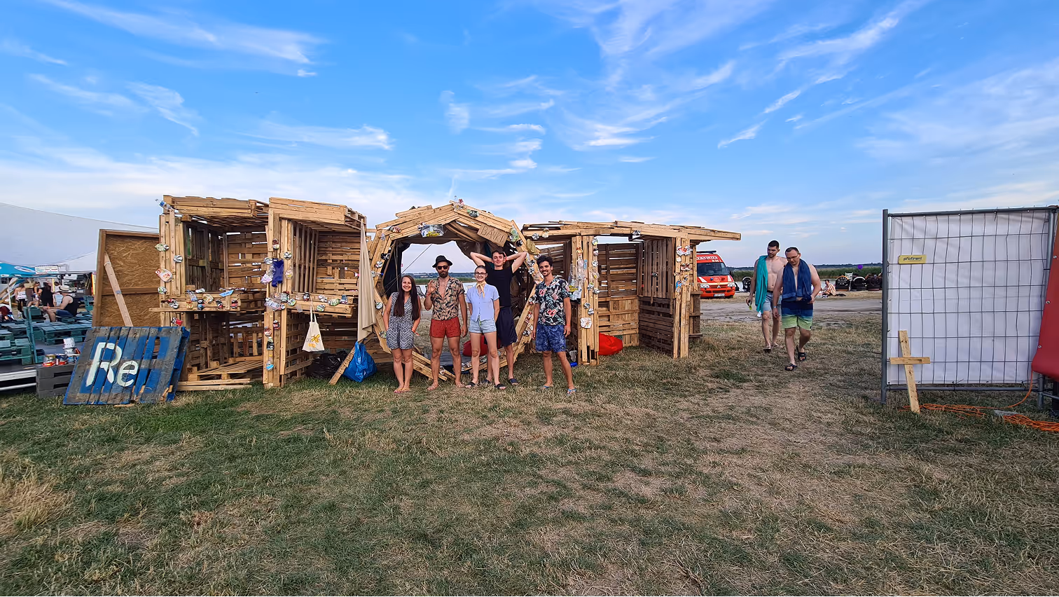 Hat fiatal áll fa szerkezet előtt füves területen, kék ég alatt, nyári szabadtéri környezetben.