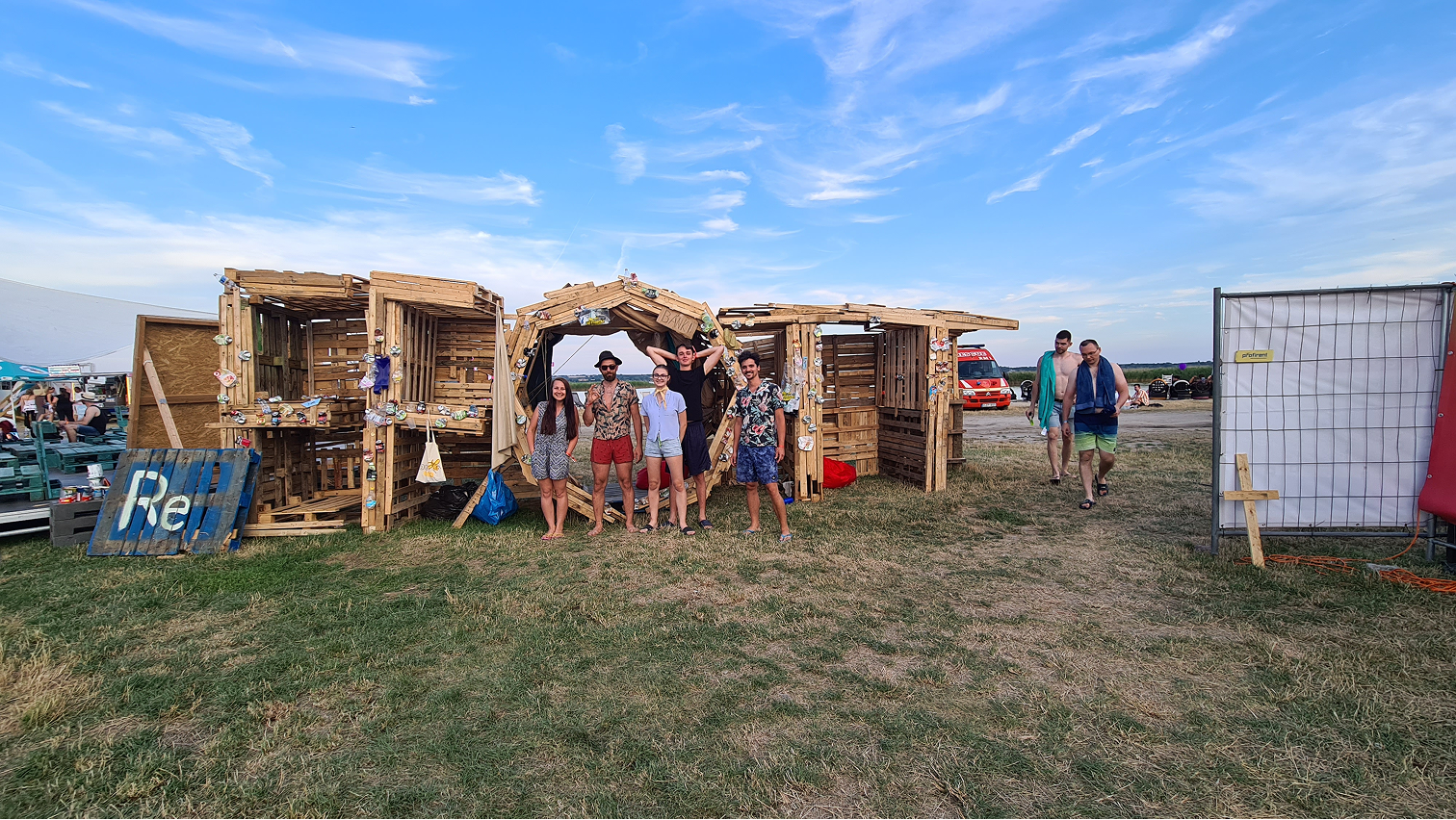 Hat fiatal áll fa szerkezet előtt füves területen, kék ég alatt, nyári szabadtéri környezetben.