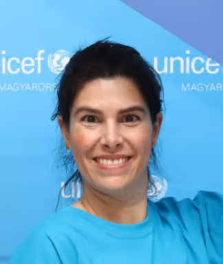 Mosolygó nő kék UNICEF háttér előtt.