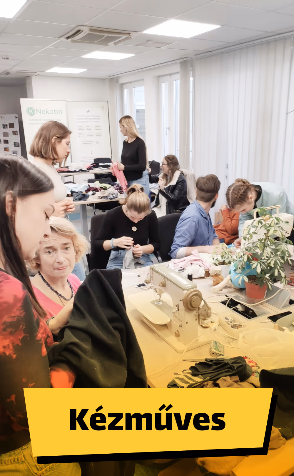 Emberek varrógép körül egy asztalnál, ruhákkal dolgozva egy jól megvilágított helyiségben.