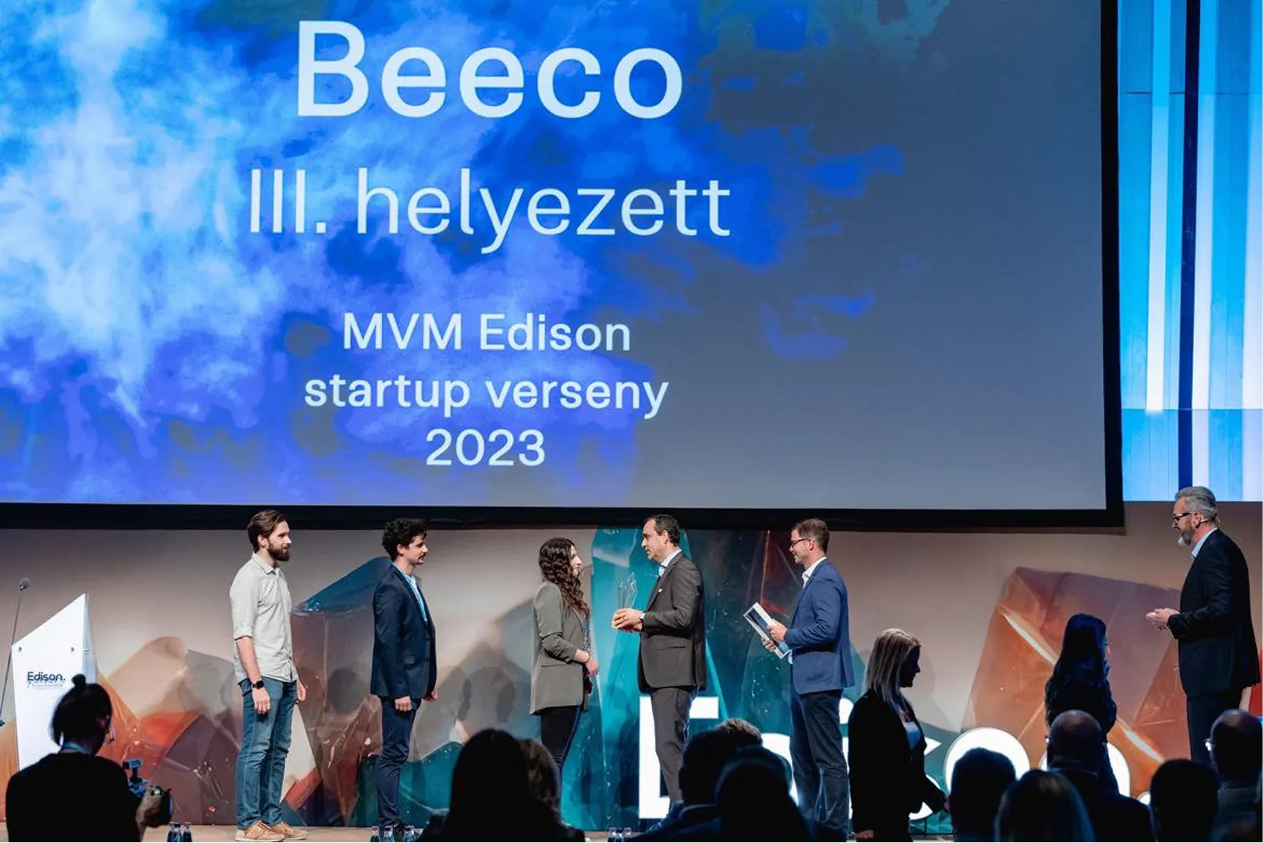 Emberek a színpadon egy díjátadón, amelyen a Beeco nyeri az MVM Edison startup verseny 2023 III. helyezett díját.