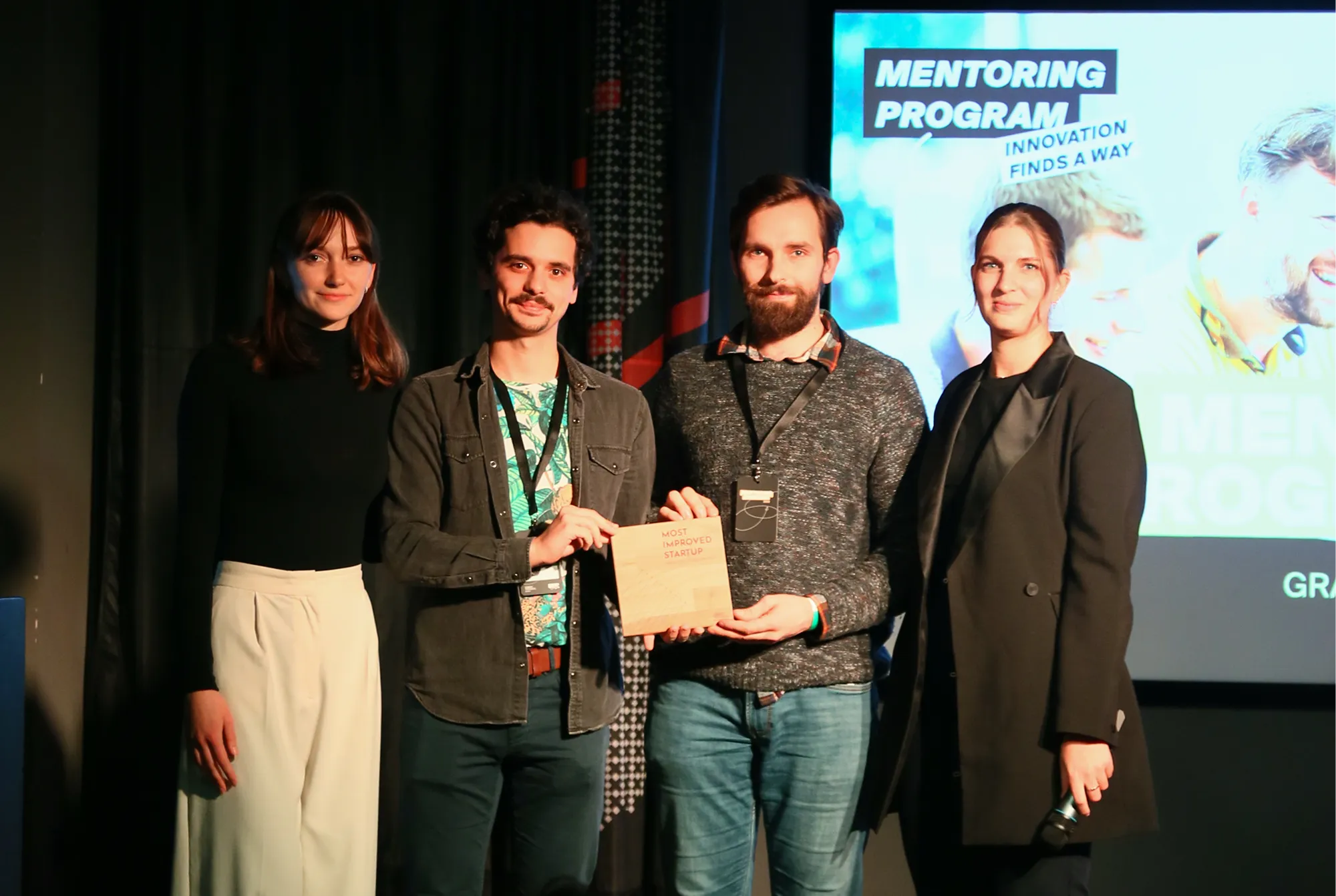 Négy fiatal áll egy színpadon, középen egy férfiakból álló páros egy "Legjobban fejlődött startup" díjat tart.