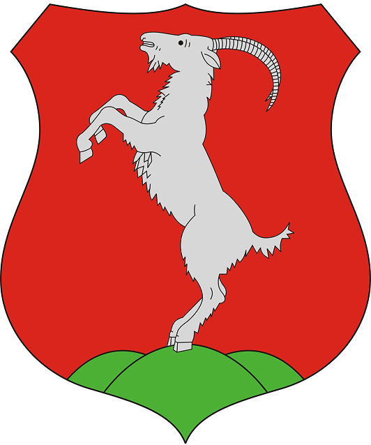 Ezüst kecske áll két lábon zöld dombokon piros pajzson.