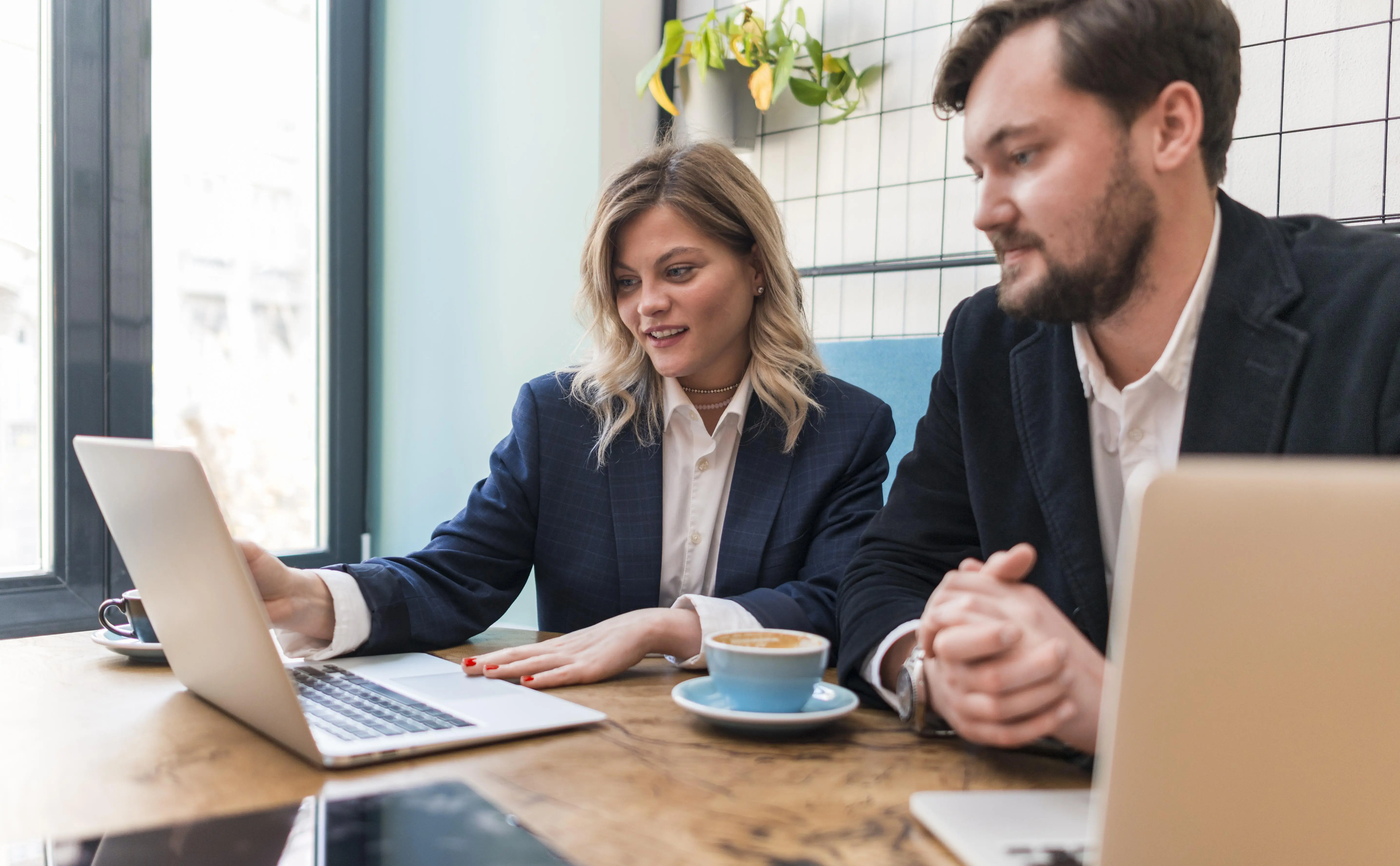 Acrevis consultants work together on a laptop on a banking project—on software from mesoneer.