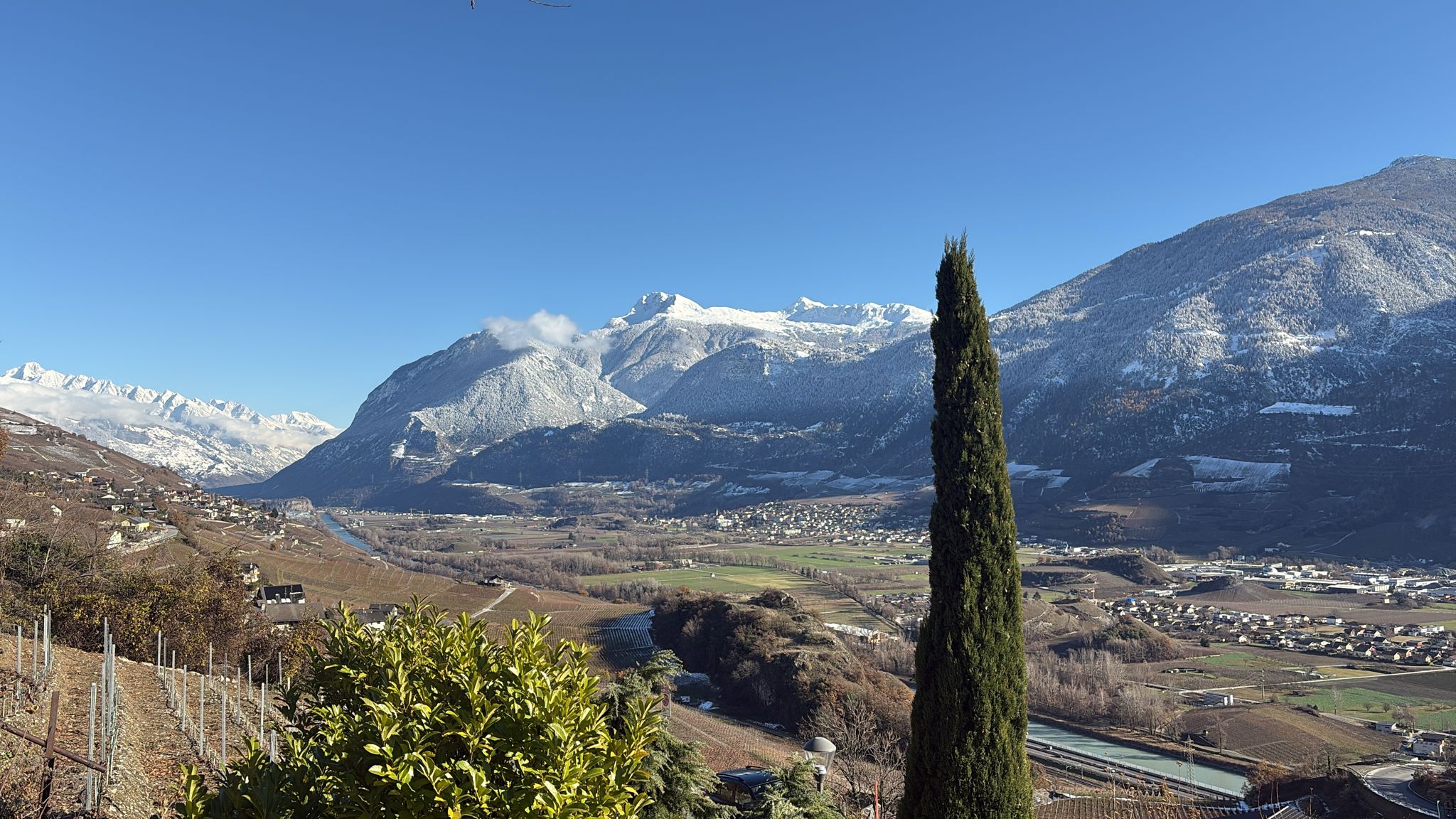 Un verre de vin blanc Cordonier Lamon tenu par une main avec en arrière-plan, de magnifiques montagnes