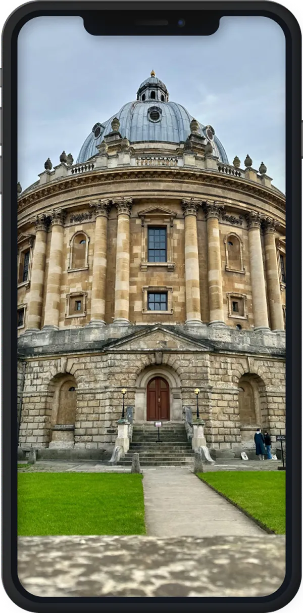 Stone domed historic building with columns and steps leading to a wooden door, viewed on a smartphone screen.
