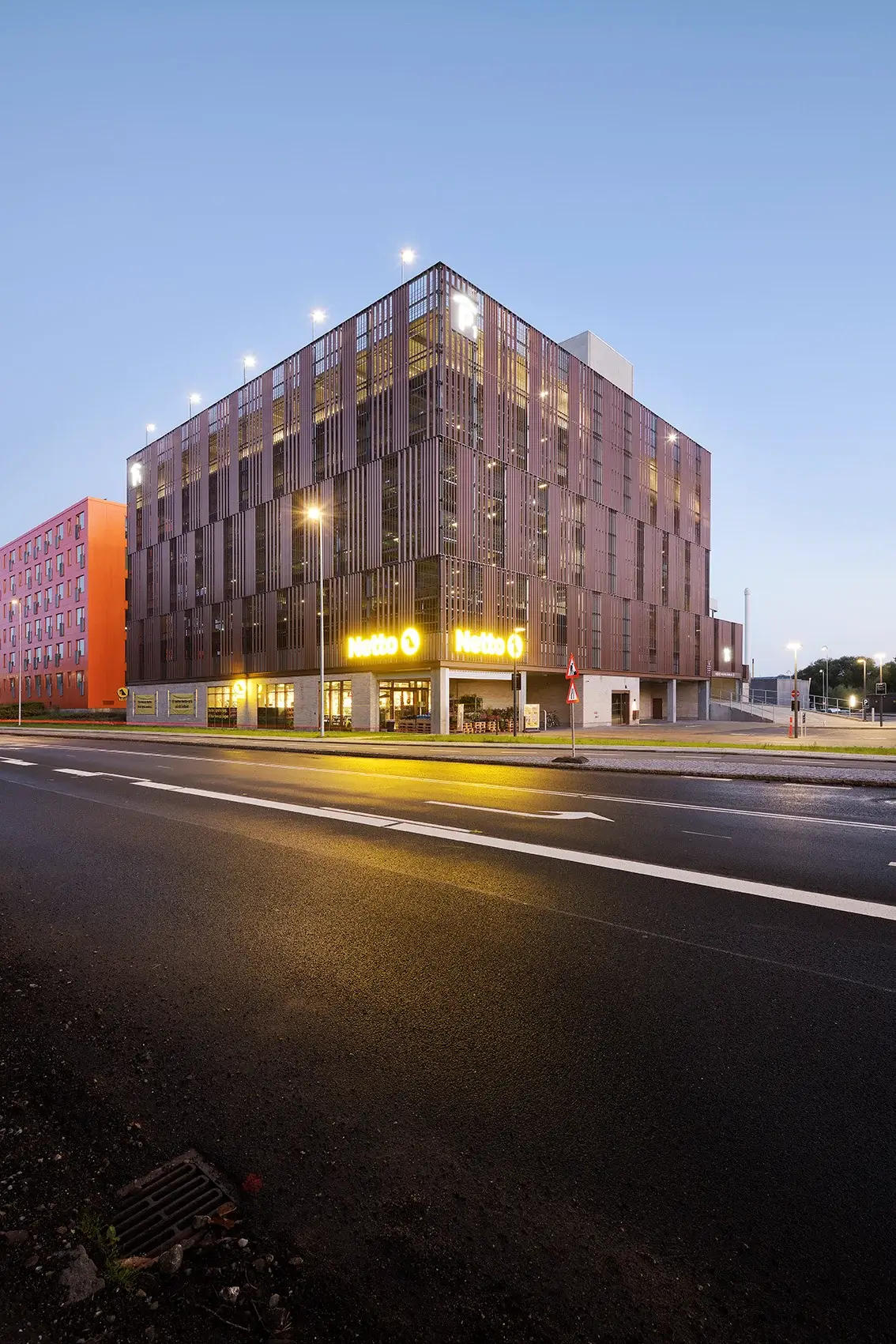 Design City Kolding p-hus i skumring med Napsu-facade af lodrette lameller i brune nuancer