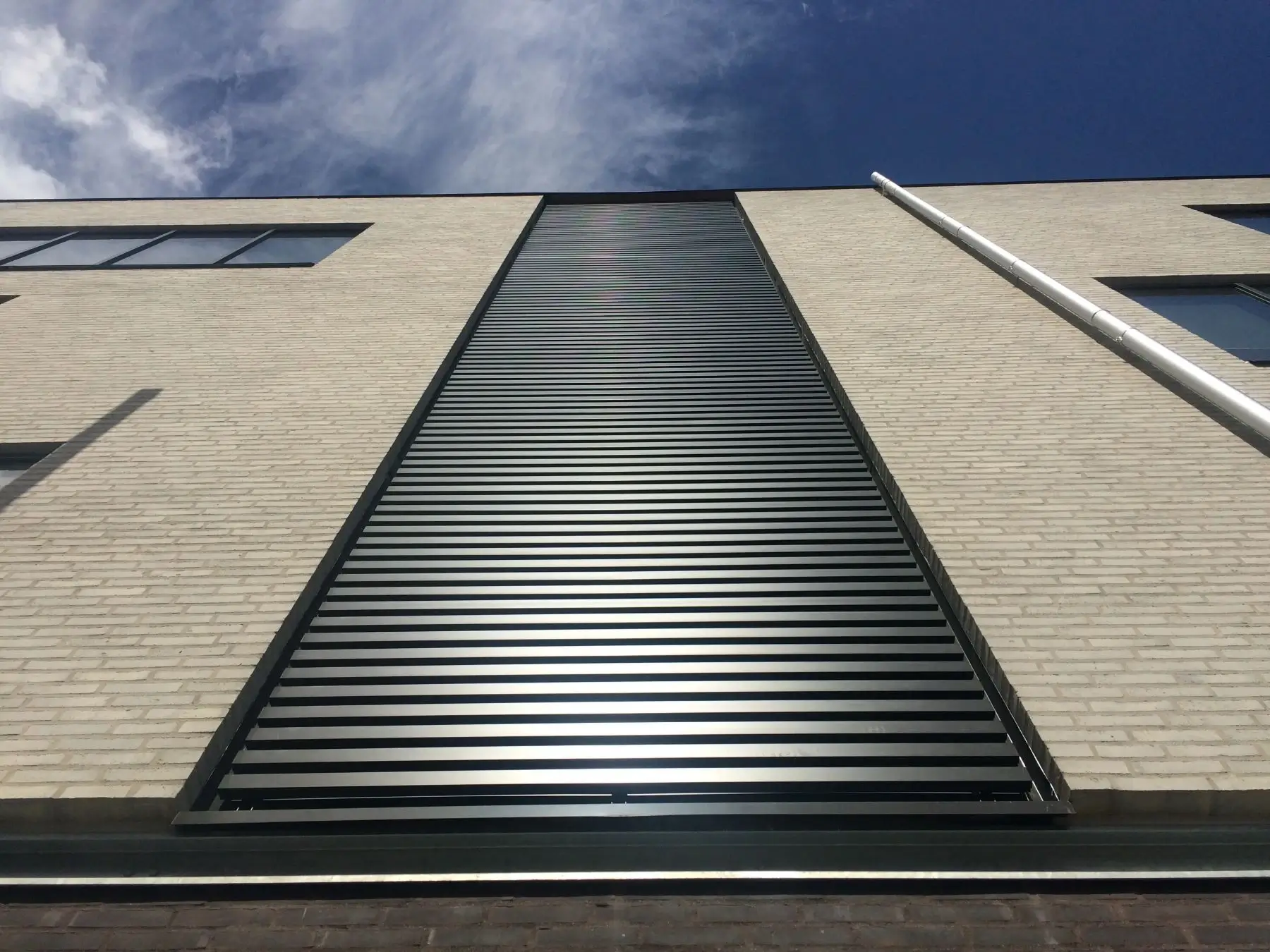 Pelican Storage med lodret felt af vandrette sorte Napsu-aluminiumslameller i lys murstensfacade