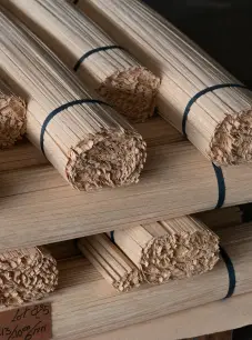 Stacks of rolled handcrafted wooden window treatments tied with black bands.