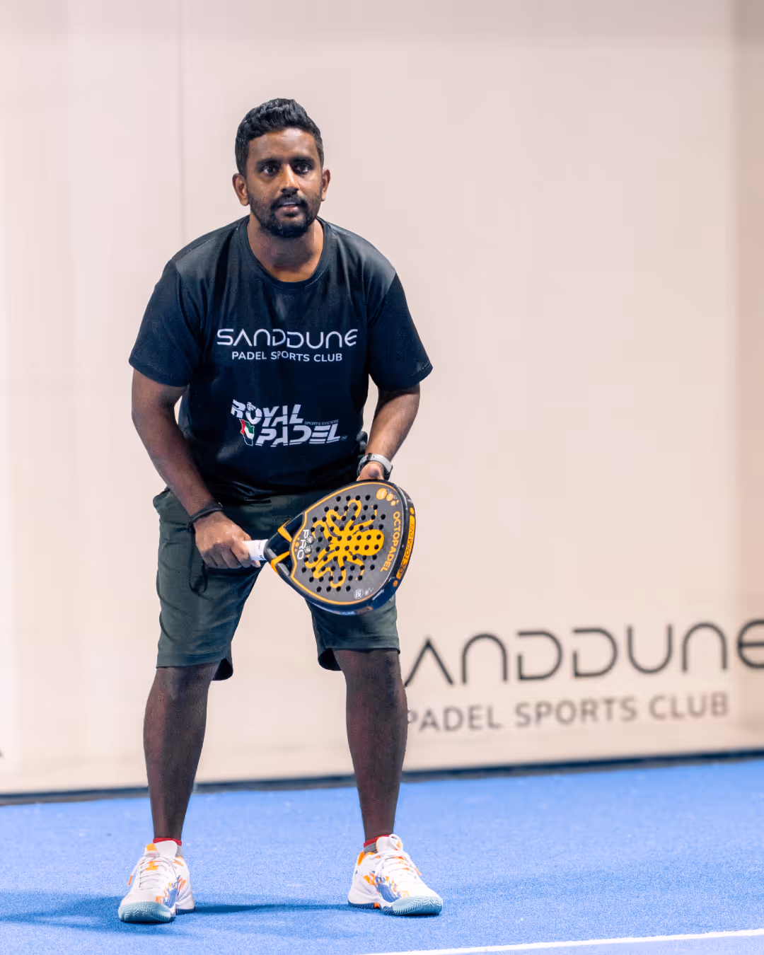 A man padel player in black padel clothing ready to start the game on the padel court