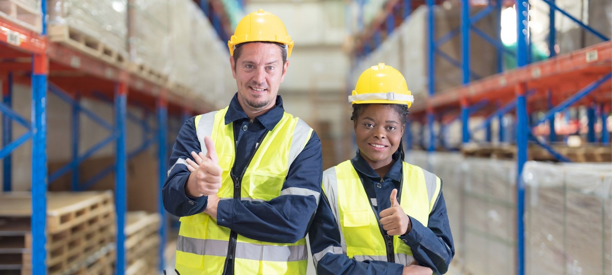 Two warehouse workers with their thumbs up