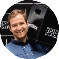 Smiling man holding two black boxes on his shoulders.