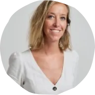 Smiling woman with shoulder-length blonde hair wearing a white V-neck blouse against white background.