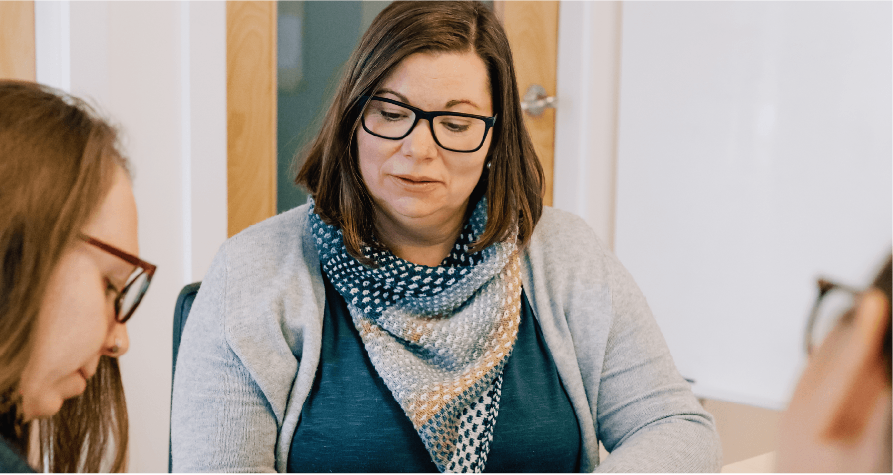 Lea Pigage looking down at paper while sitting at board room table