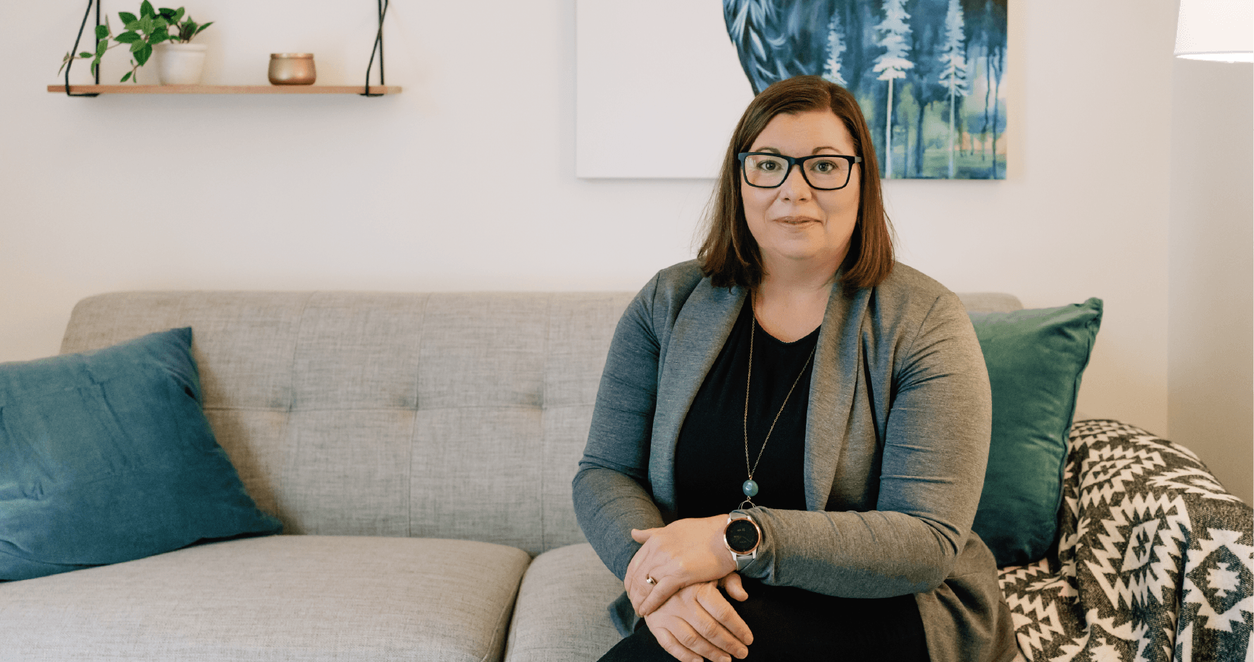 Lea Pigage sitting cross legged on a couch in an office