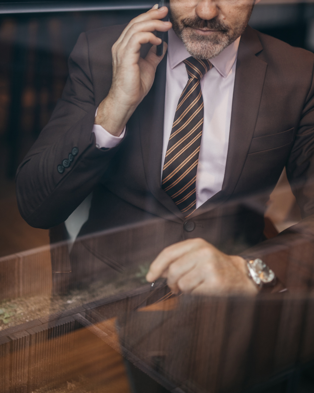Modern, open-air room with floor-to-ceiling windows overlooking a calm ocean. Wooden lounge chairs facing the water, with tall grasses near the edge.