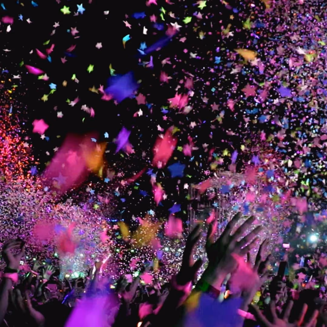 Event with confetti coming down and a crowd of hands in the air
