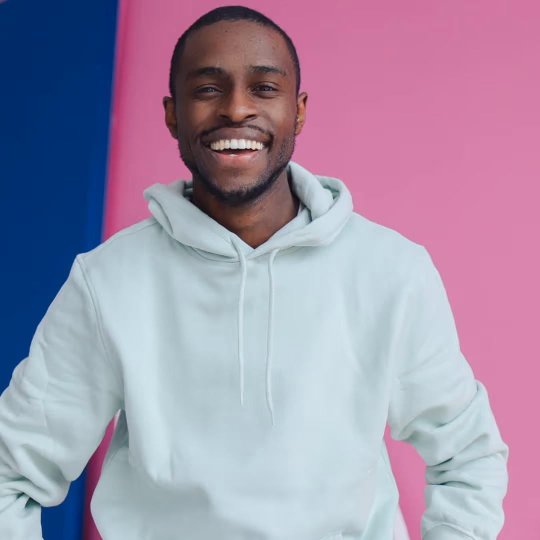 Image of a man smiling in a white hoodie with brightly colored background