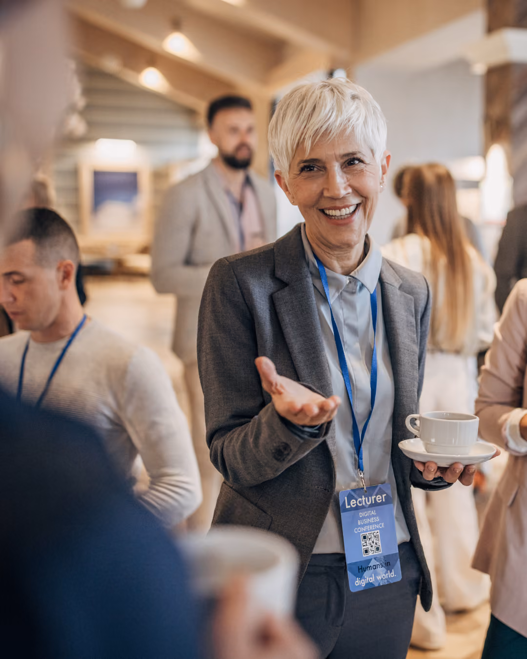 Woman at an event with a speaker pass on and holding a mic. 