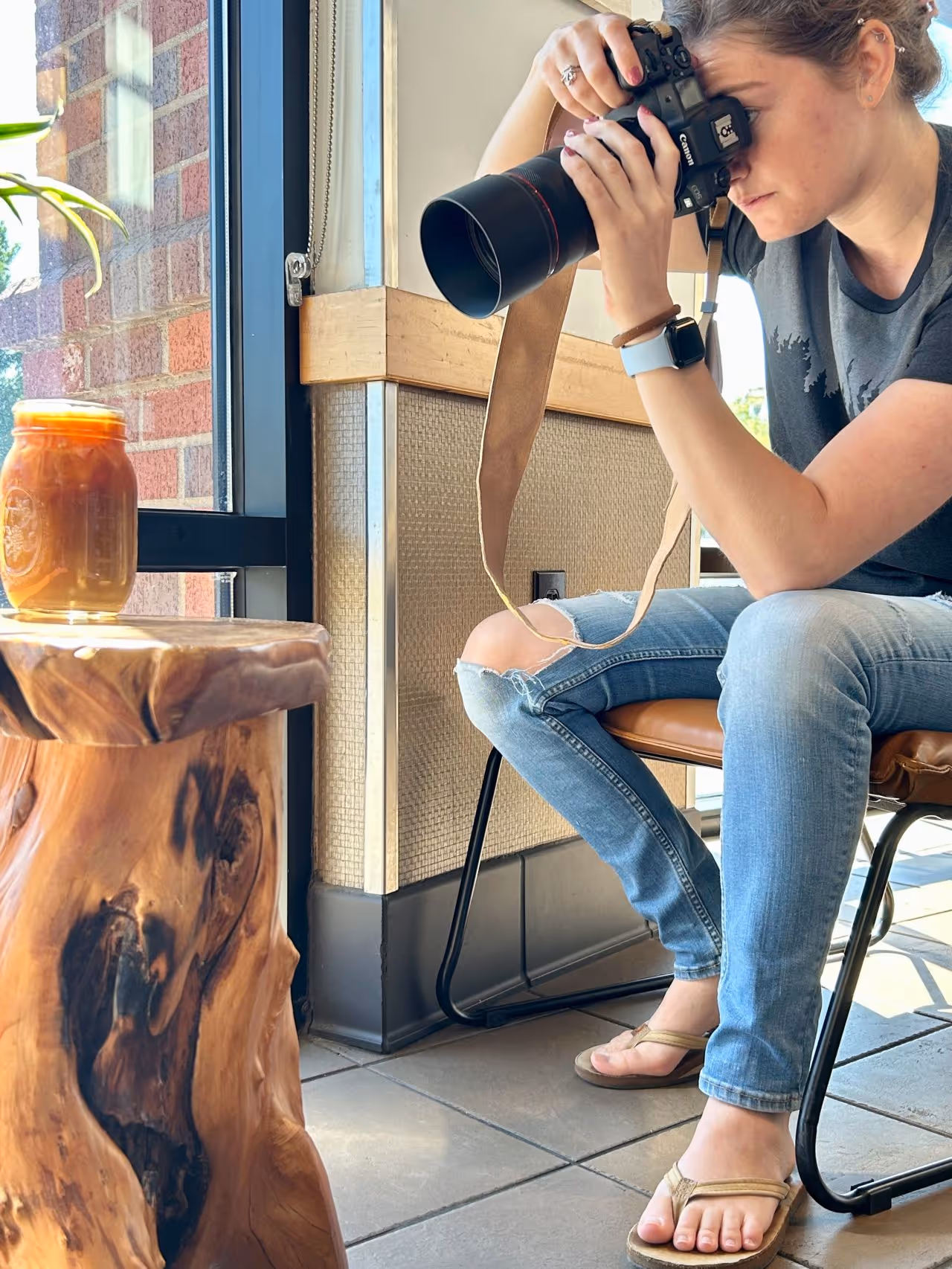 Headshot of Kayla turning towards the camera and smiling while standing in front of a waterfall and holding her own camera.