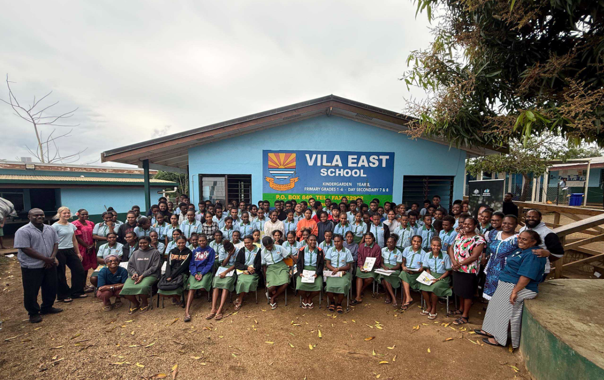 schoolchildren sitting outside Vila East School smiling for photo