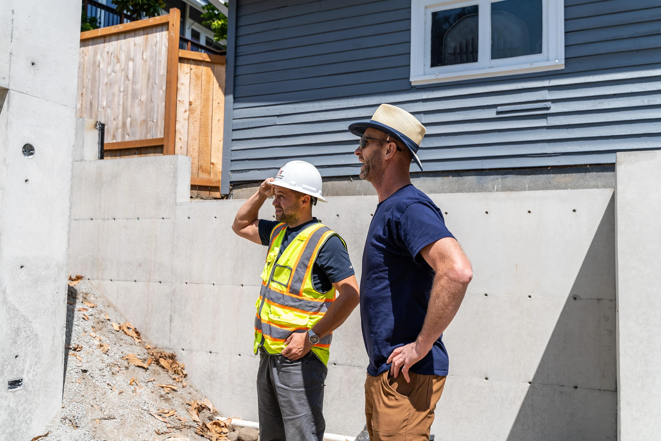 Aces Four project lead in safety gear reviewing job site progress alongside a homeowner.