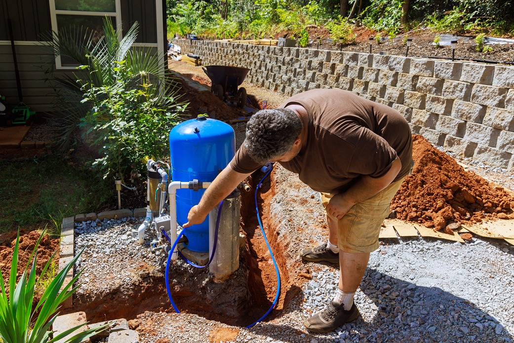 Man installing a sewage pump outside a residential property